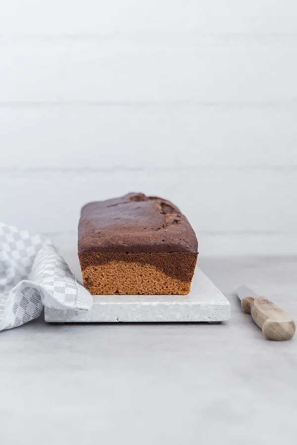 Frisch gebackener Marmorkuchen auf einem Scheidebrett, daneben liegt ein Messer.