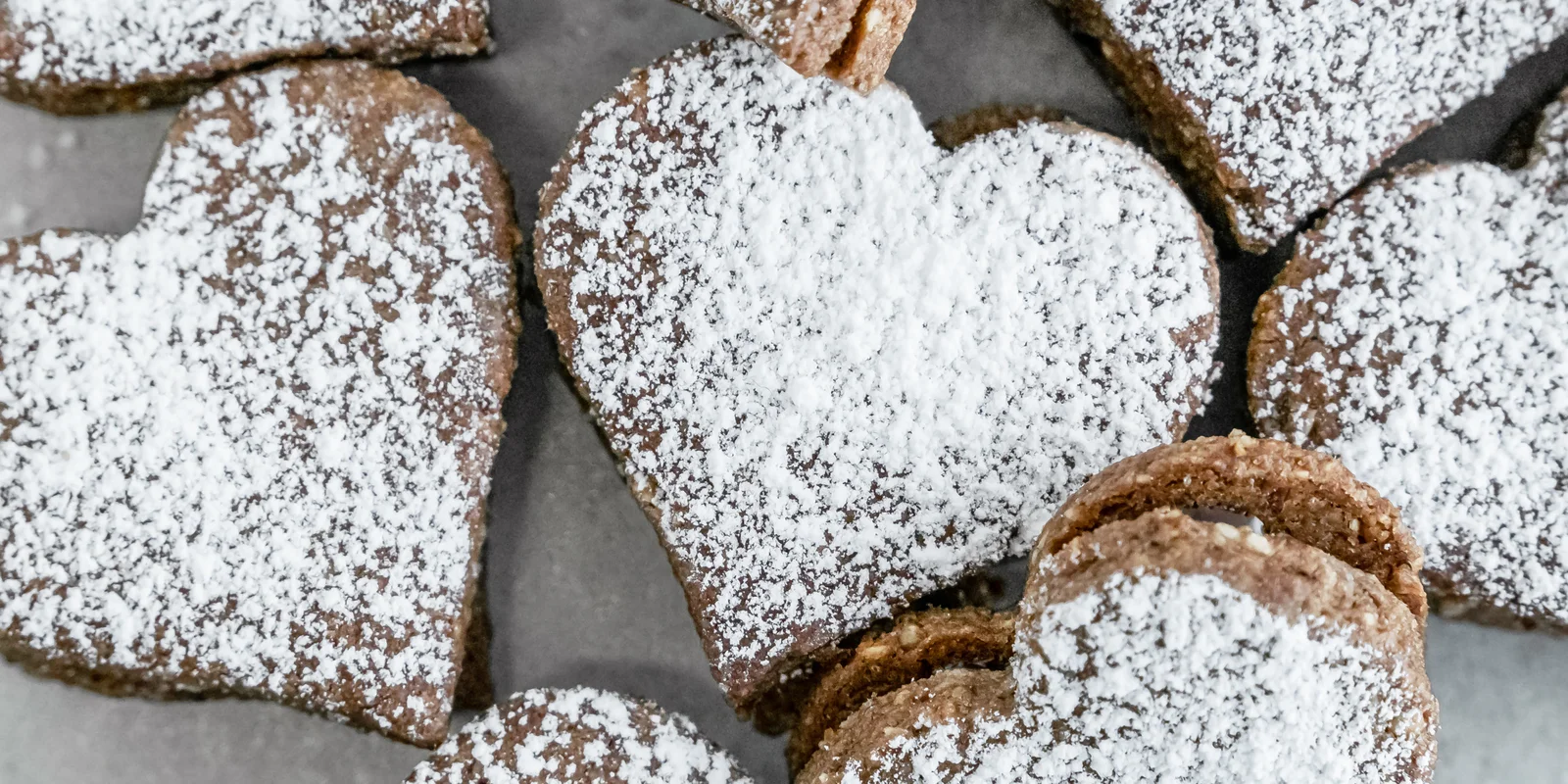 Mehrere fertige Vegane Schokoherzen mit Puderzucker bestreut nebeneinander